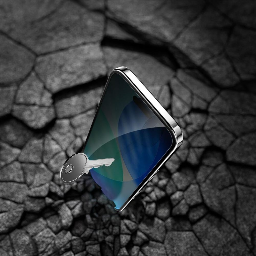 A shiny key rests on a smartphone screen against a dark stone background.