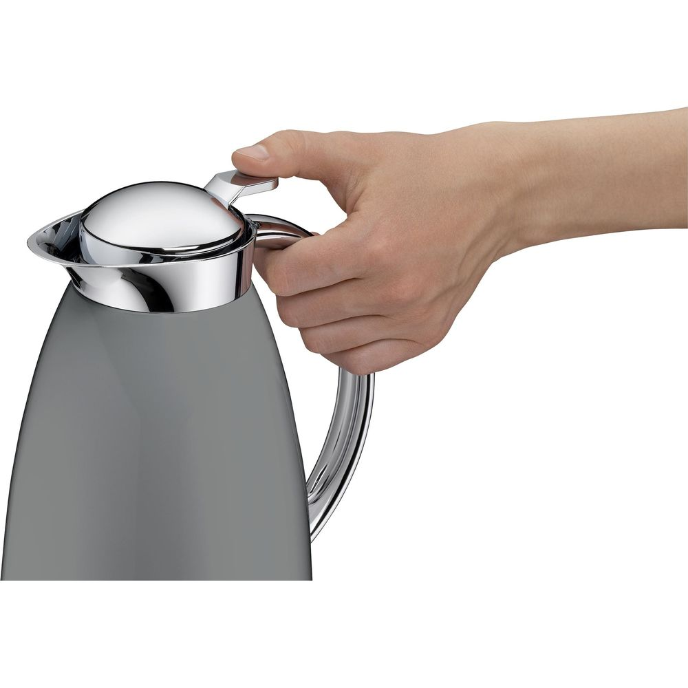 Une main tient un thermos gris aux accents chromés.