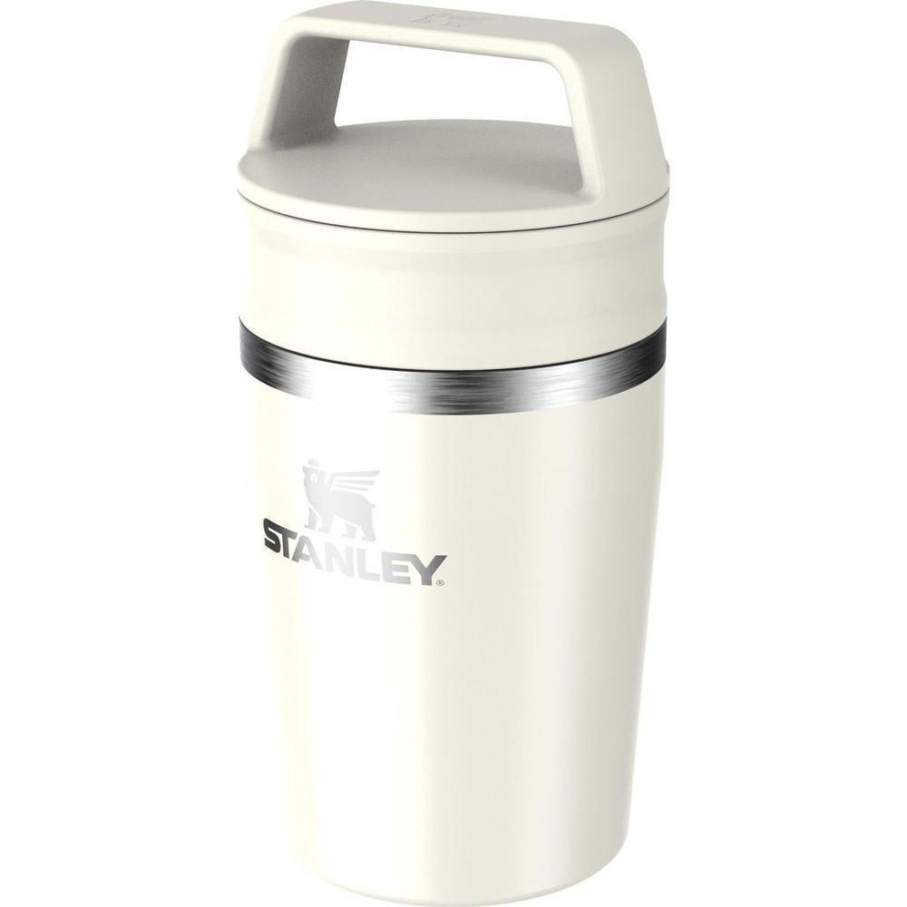 Ein cremefarbener Stanley-Becher mit silbernem Band und Griff.