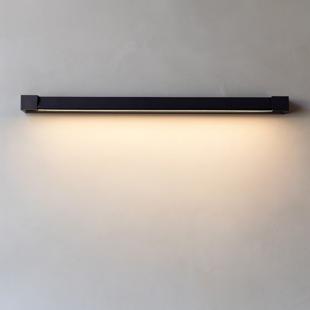 Una sottile barra luminosa a LED nera illumina una parete grigia.