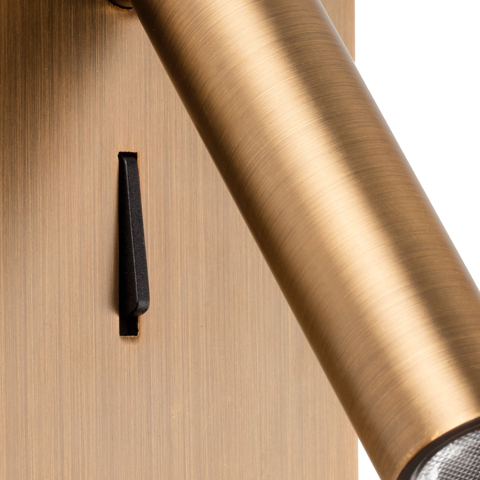 Un interruttore in bronzo su una lampada da parete con finitura spazzolata.
