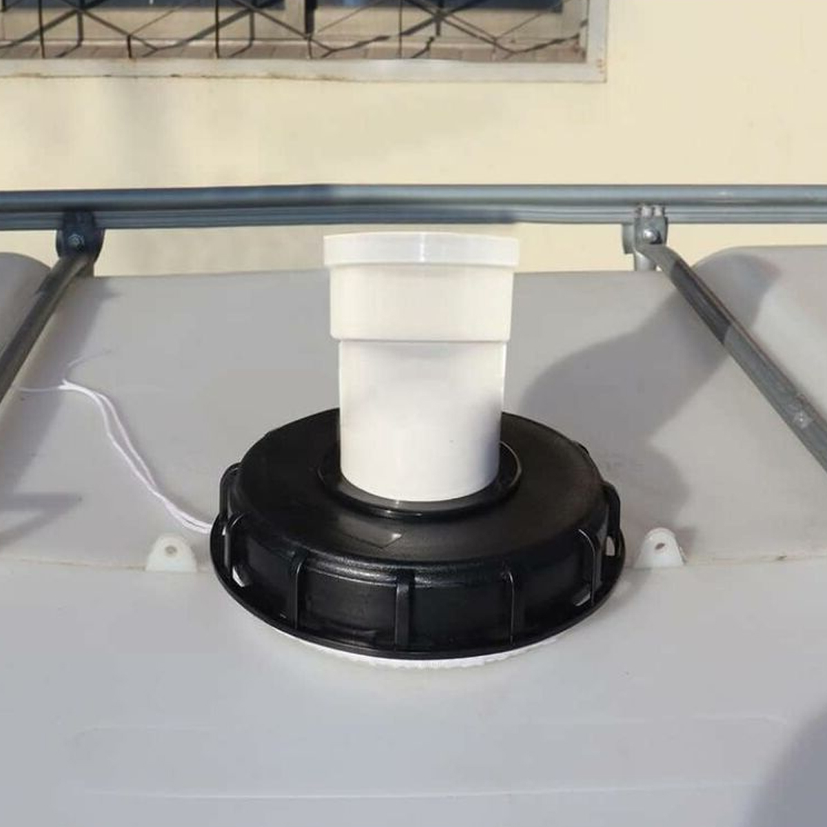 Weiße Kunststoffkappe auf schwarzem Gewinde auf einem weißen Tank. Metallrohr oben.