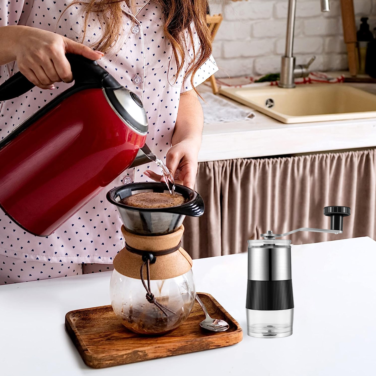 Eine Frau gießt Wasser aus einem roten Wasserkocher in einen Kaffeefilter. Daneben steht eine Kaffeemühle.
