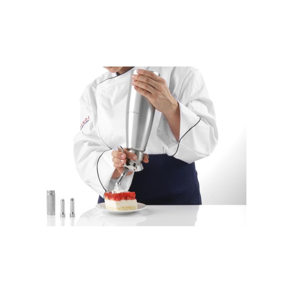 Eine Person in Kochuniform dekoriert einen Kuchen mit Schlagsahne aus einem Sahnespender.