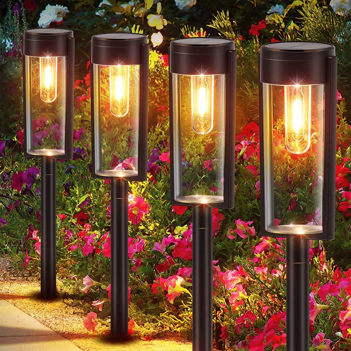 Vier Solarleuchten mit Glaszylindern und Glühbirnen leuchten vor einem Hintergrund aus bunten Blumen.