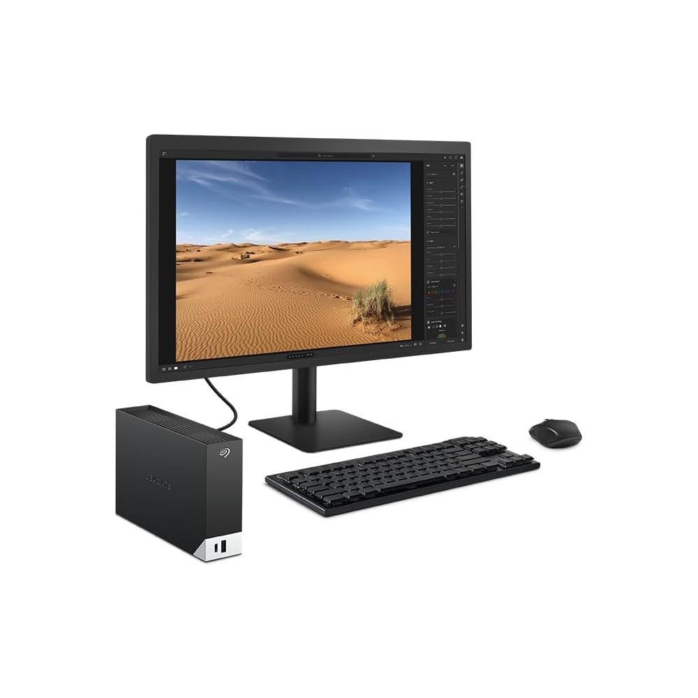 Ein Monitor zeigt eine Wüstenlandschaft. Daneben stehen eine externe Festplatte, Tastatur und Maus.