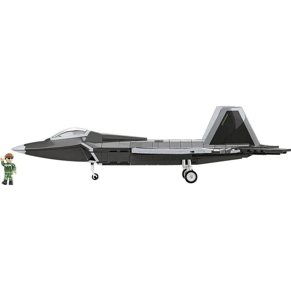 Szary model myśliwca z pilotem obok na białym tle.