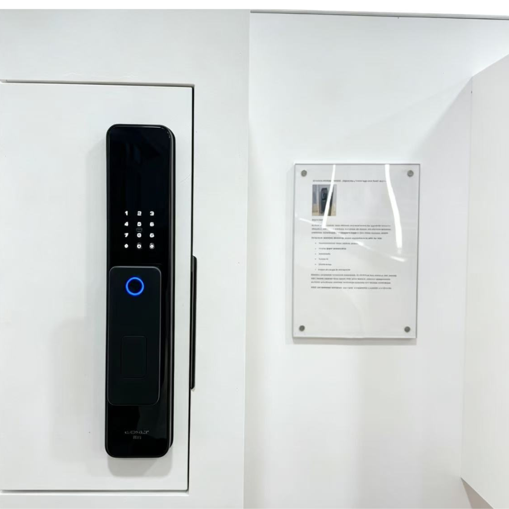 Un tirador de puerta digital negro con teclado y luz azul en una puerta blanca junto a una hoja informativa.
