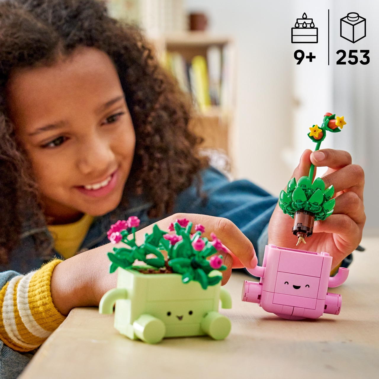 Dziewczynka buduje różowe i zielone doniczki LEGO z roślinami.