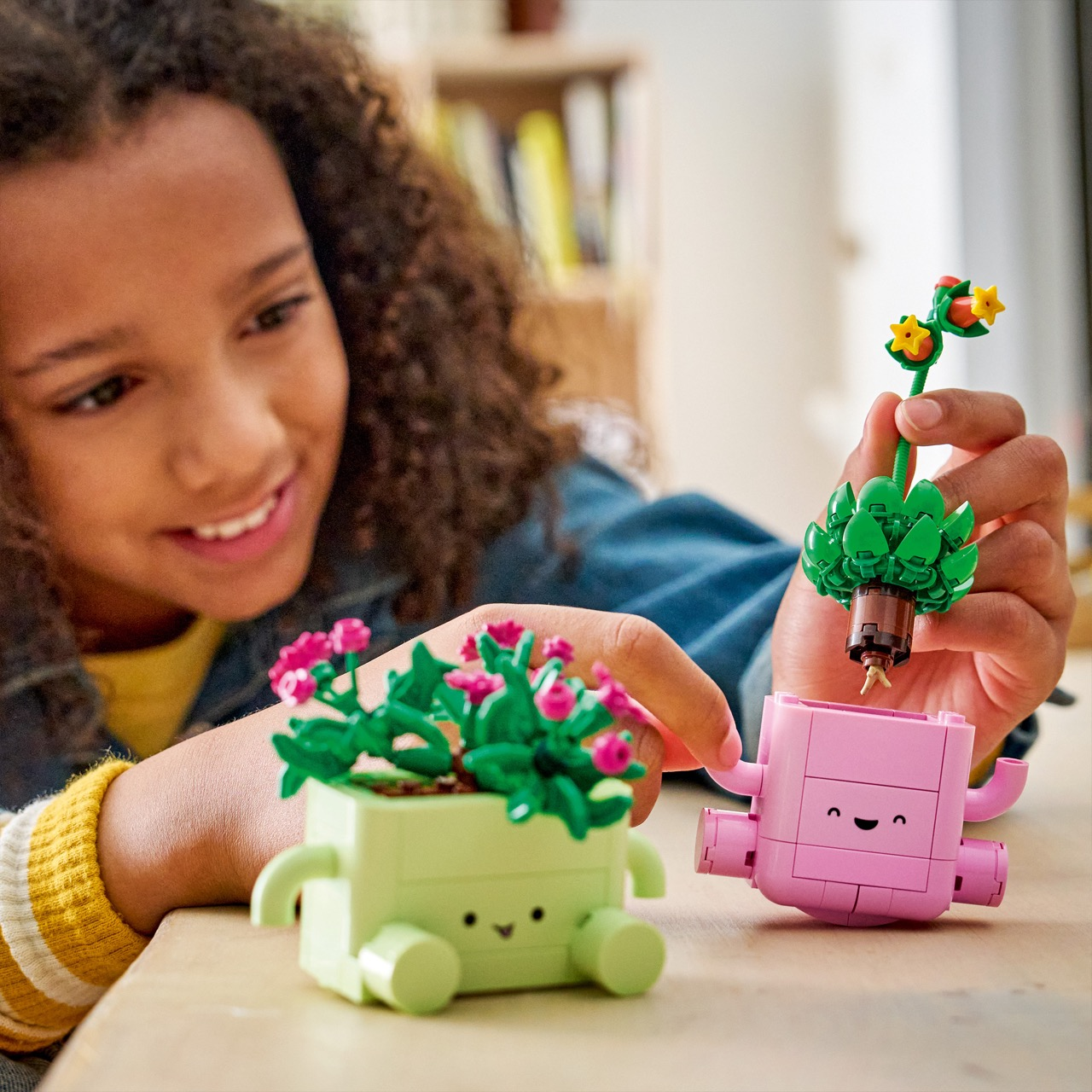 Dziewczynka buduje doniczki Lego z twarzami i ramionami.