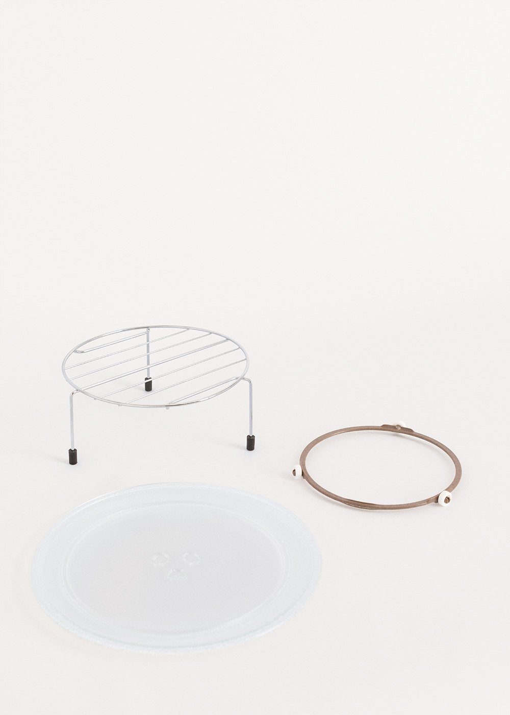 Un plateau en verre rond, une grille métallique et un anneau brun sur fond blanc.
