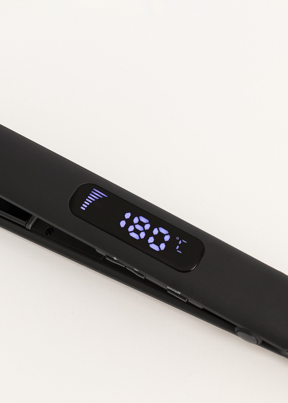 Plancha de pelo negra con pantalla digital que muestra 180°C y barra de calor.