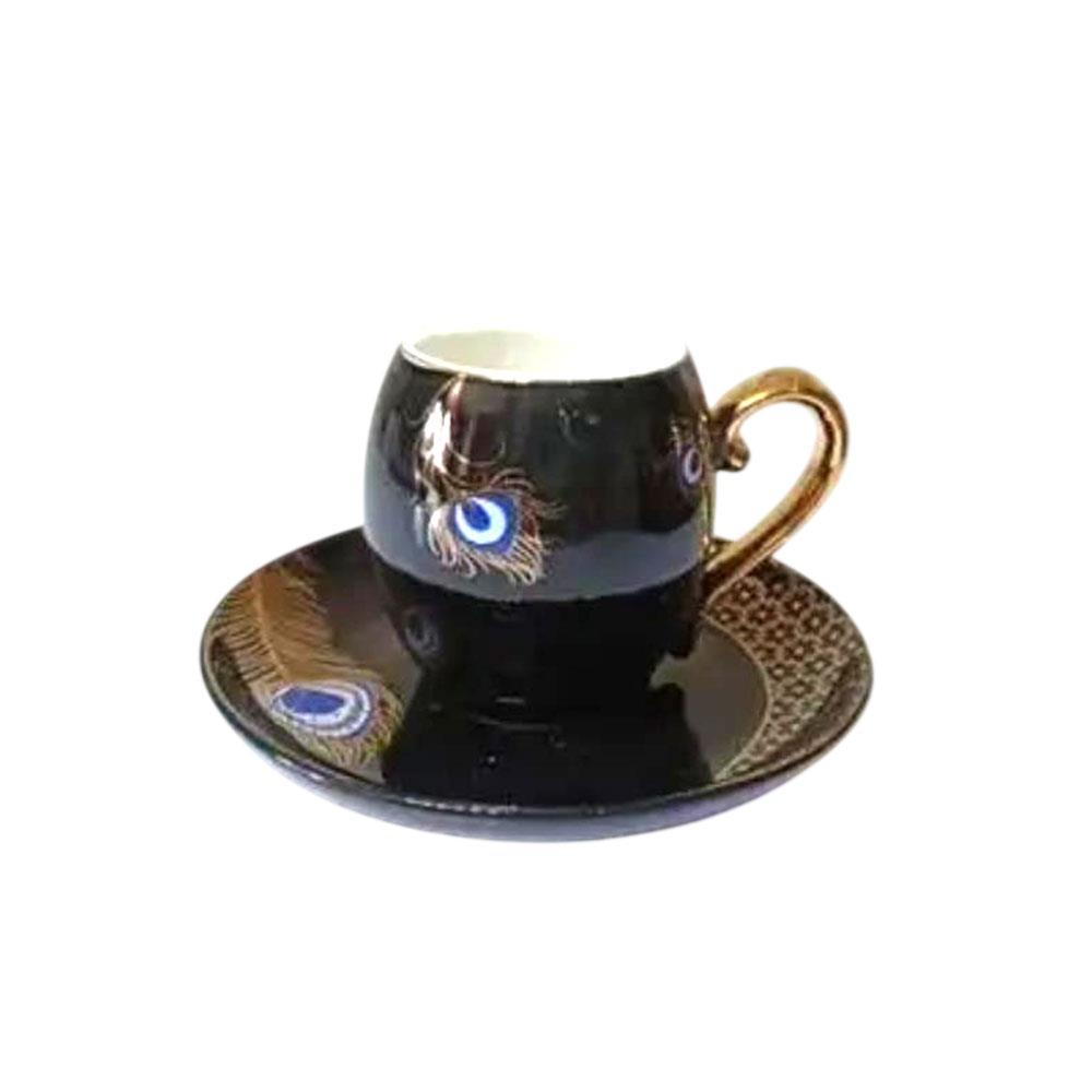 Tepsi üzerinde altın kulplu, peacock tüy desenli siyah kahve fincanı.