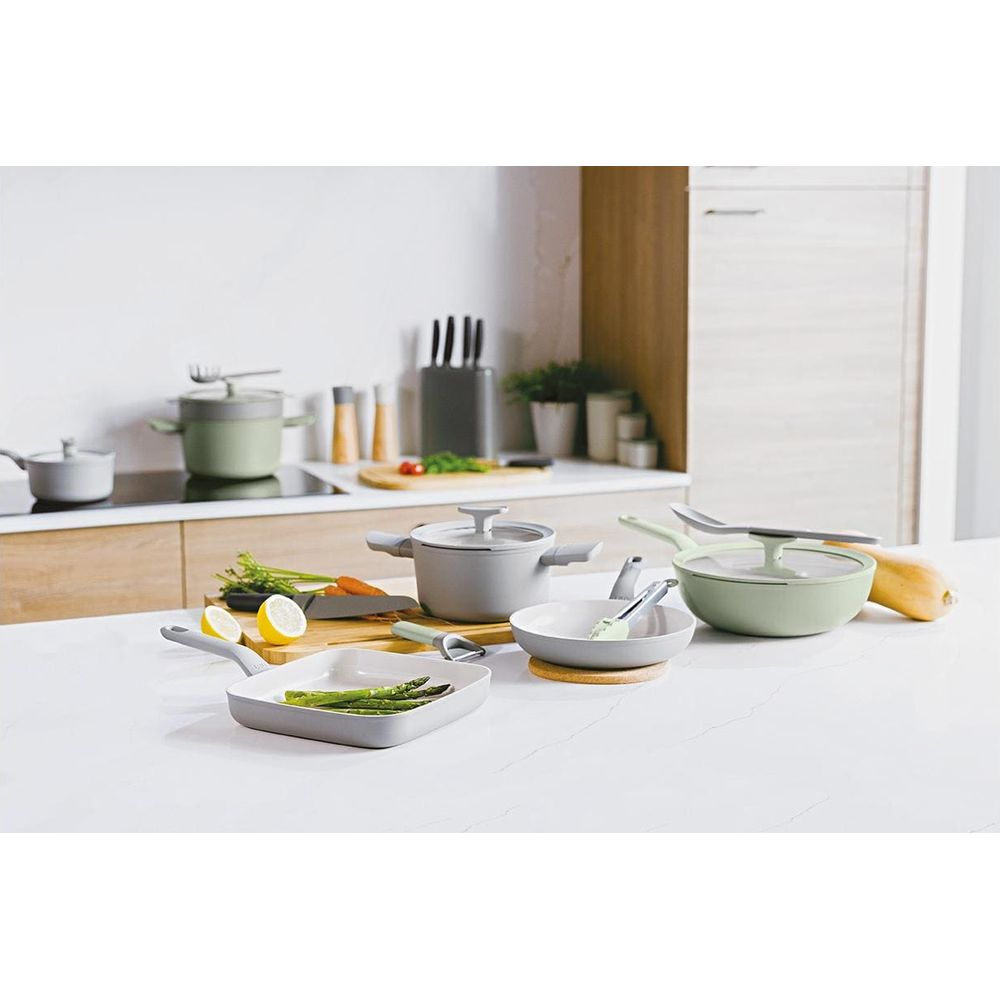 Kitchen scene with various cookware, vegetables, and utensils on a countertop.