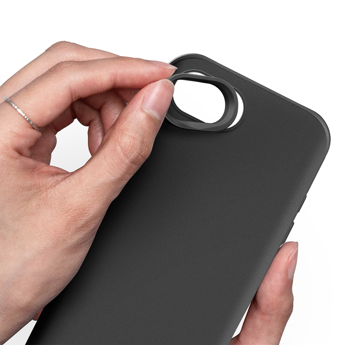 Een hand met een ring plaatst een zwarte ring op een zwarte telefoon.