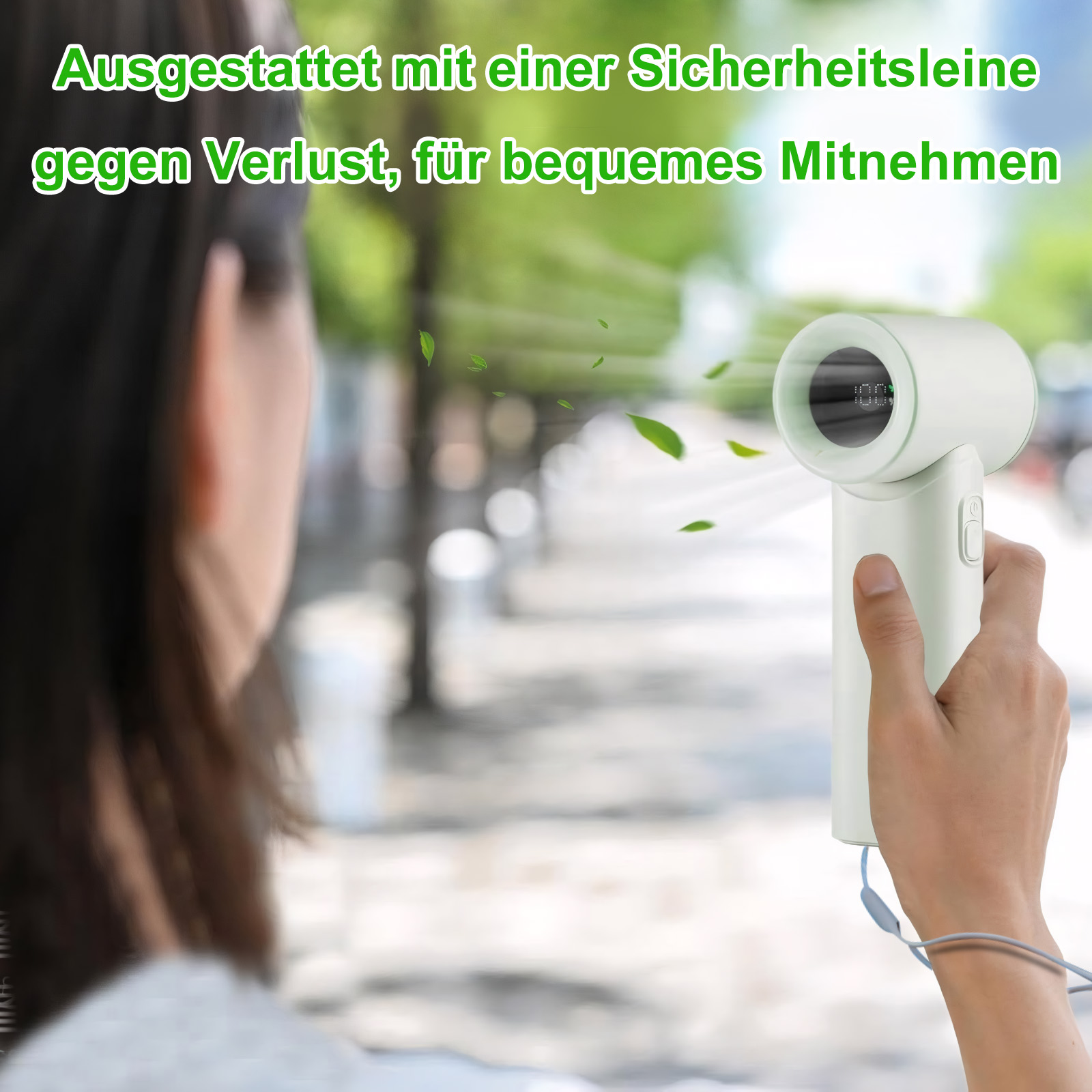 Hand hält hellgrünen Ventilator mit Display. Grüne Blätter wehen.
