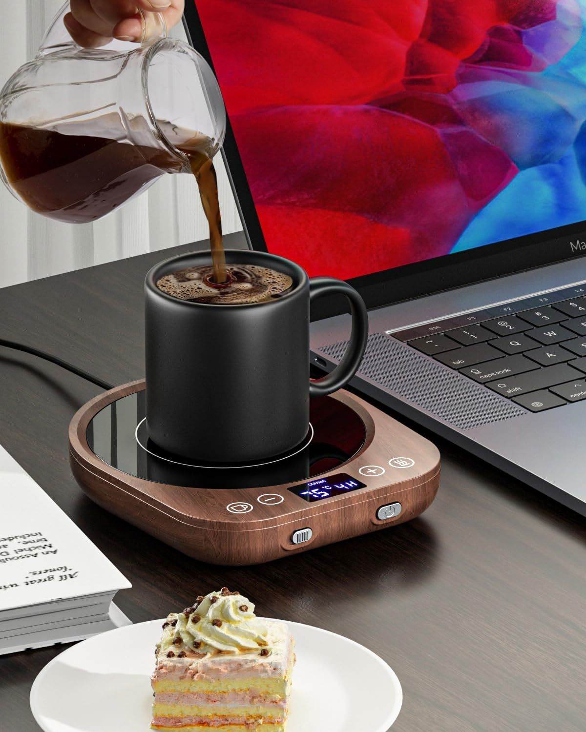 Kaffee wird in eine schwarze Tasse auf einem Heizgerät gegossen. Ein Kuchen liegt daneben.