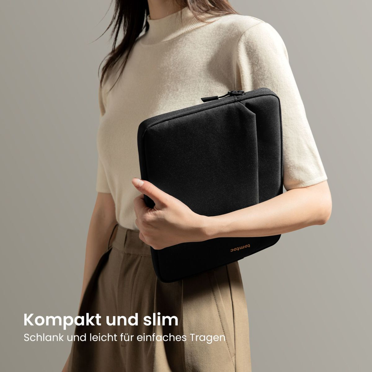 Person hält eine schlanke schwarze Laptoptasche. Text: Kompakt und slim.