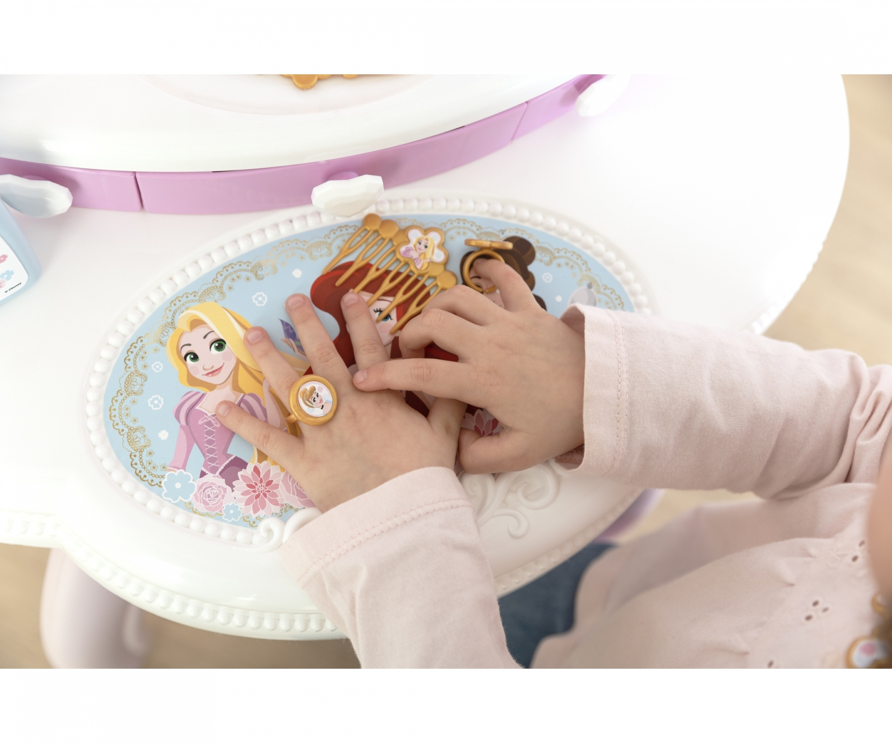Bambino gioca con una toeletta da principessa con disegni di Rapunzel e Ariel.