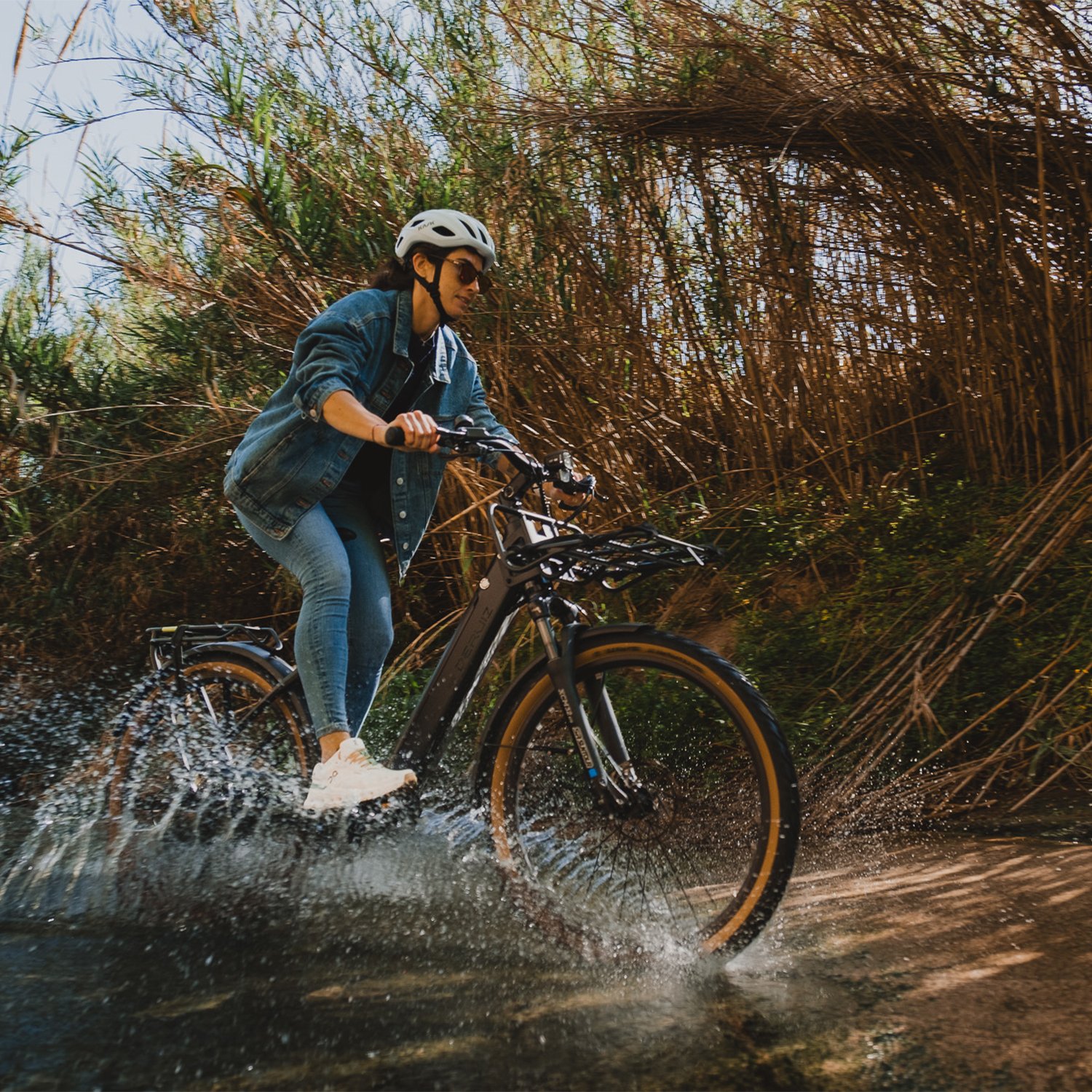 Eine Person fährt mit einem Fahrrad durch Wasser, das von den Rädern aufspritzt.