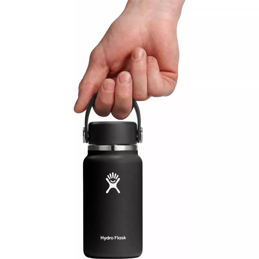 Eine Hand hält eine kleine schwarze Hydro Flask Flasche am Henkel.