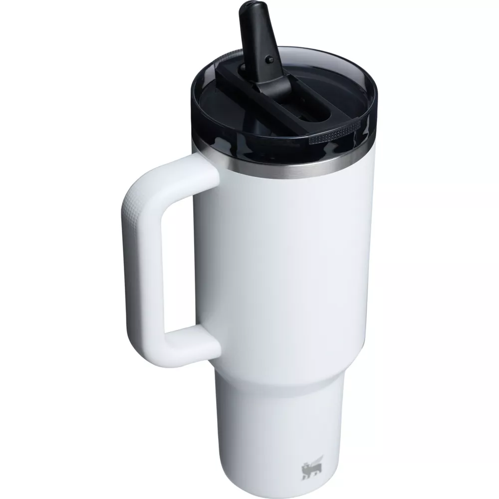 Siyah kapaklı ve pipetli beyaz termos bardak, gümüş kenarlı ve beyaz saplı. Stanley logosu.
