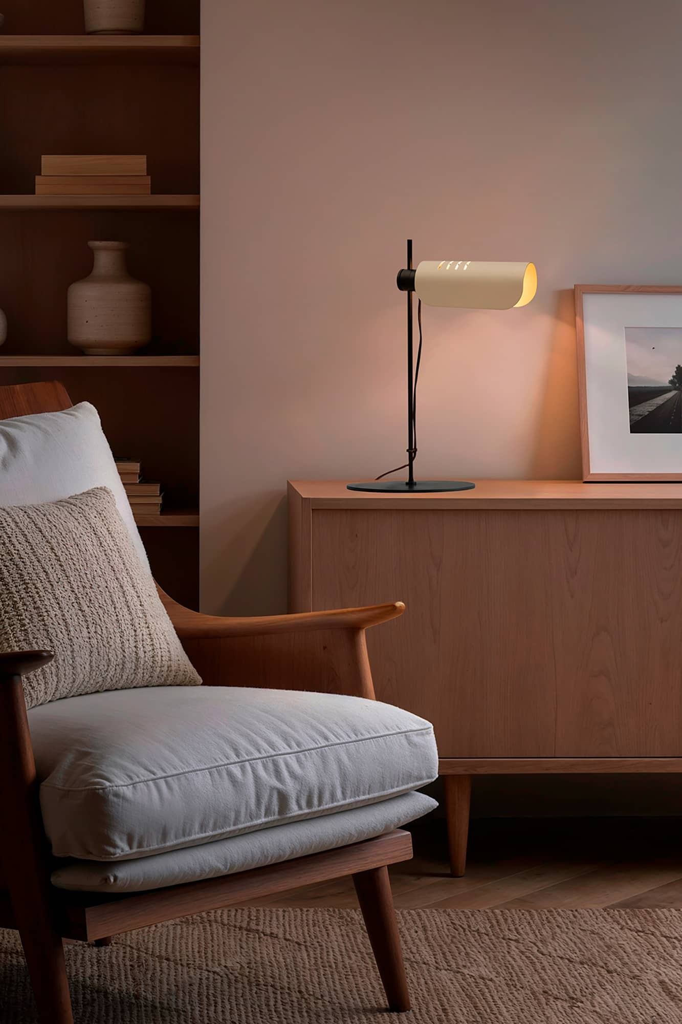 Una poltrona con cuscini davanti a un mobile con lampada e quadro.