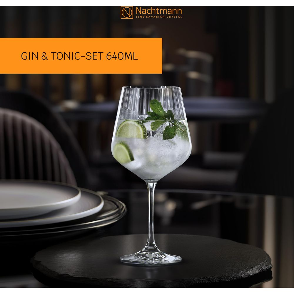 Ein Glas Gin Tonic mit Eis, Limettenscheiben und Minze auf einem Tisch.