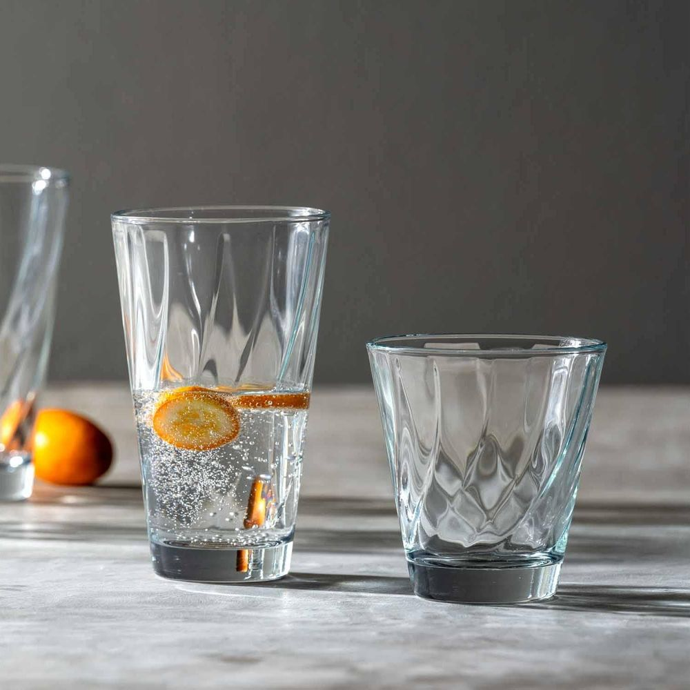 Drei Glaser auf einem Tisch, eines mit Wasser und Orangenscheiben.