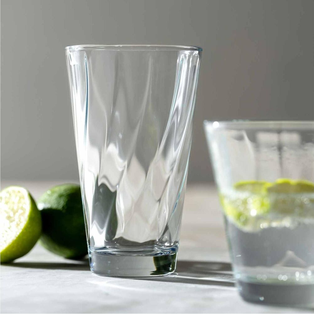 Zwei Gläser auf einem Tisch, eines mit Limettenscheiben, daneben zwei Limettenhälften.
