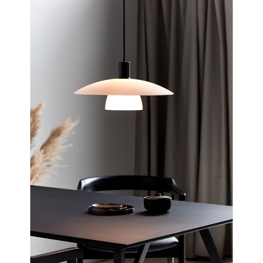 Une suspension au-dessus d'une table noire avec des assiettes et un bol.