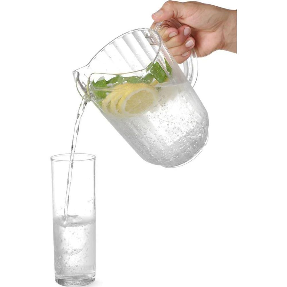 Una brocca di acqua con limone e menta viene versata in un bicchiere.