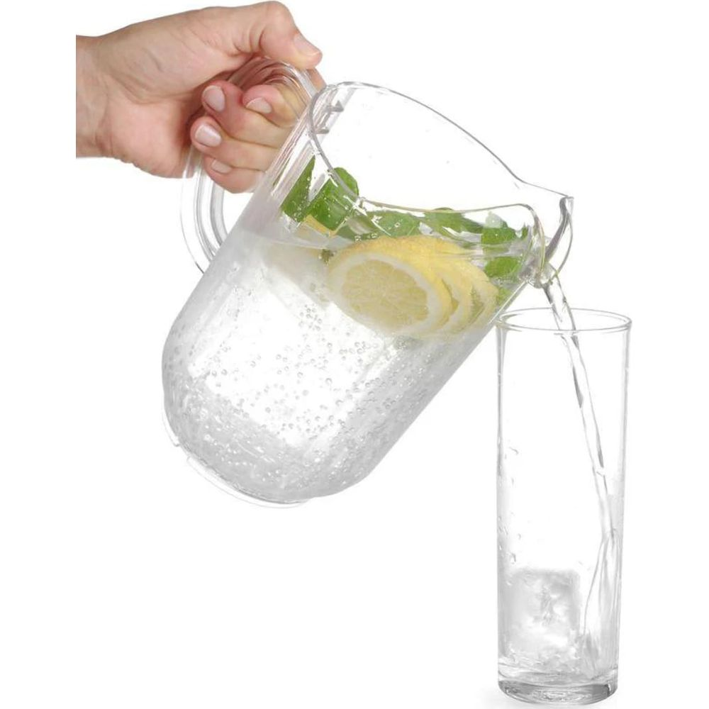 Una mano versa acqua con limone e menta da una brocca in un bicchiere con ghiaccio.