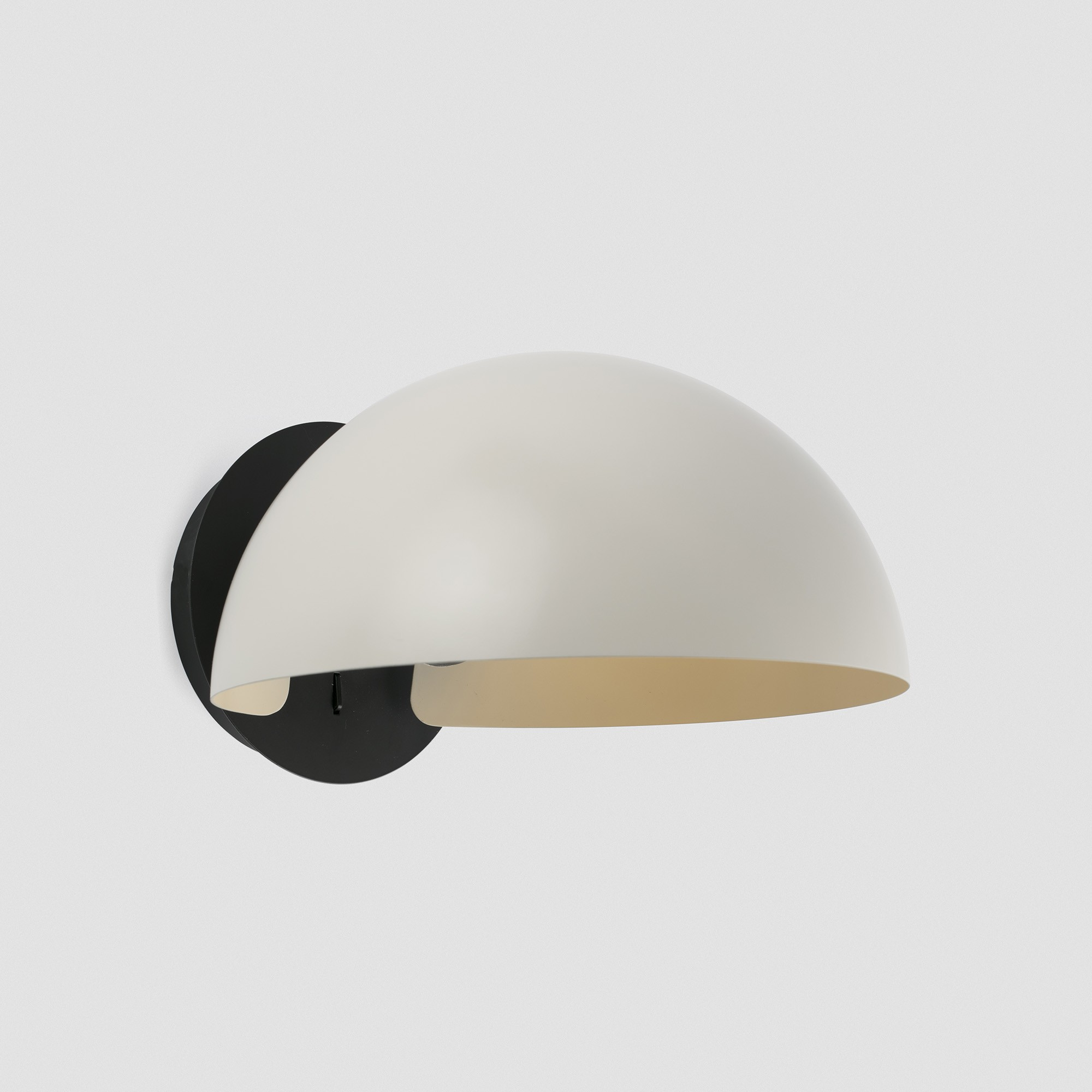 Una lampada da parete moderna con base nero opaco e paralume a cupola color crema.