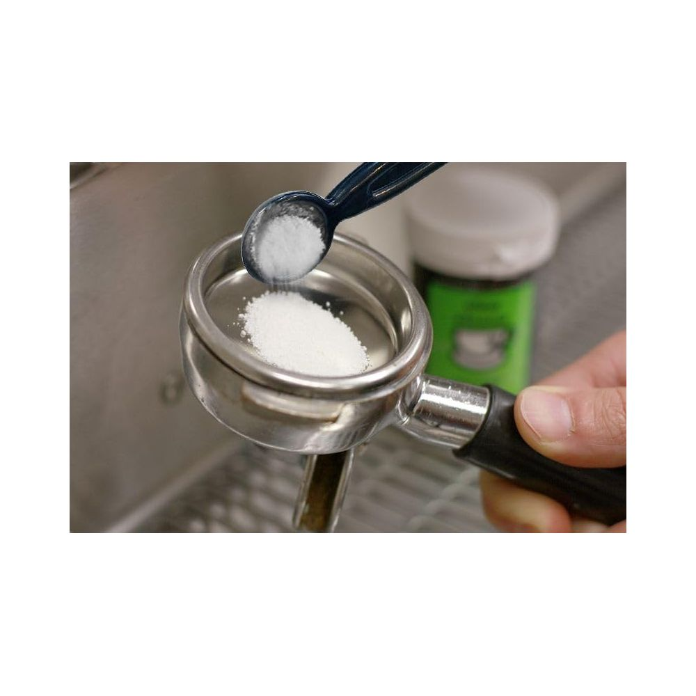 Polvere versata in un portafiltro per espresso con un cucchiaio, contenitore sullo sfondo.