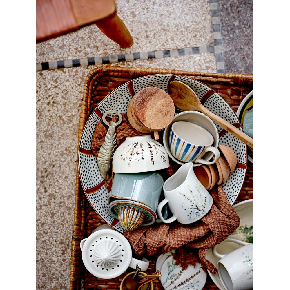 Un panier d'articles de cuisine comprenant un presse-agrumes, des cuillères en bois et des bols en céramique.