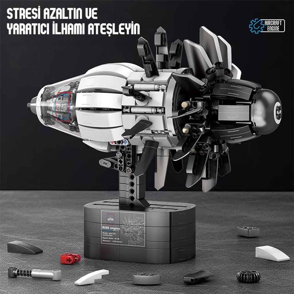 Siyah stand üzerinde beyaz ve siyah jet motorunun detaylı modeli. Etrafa saçılmış bazı parçalar.