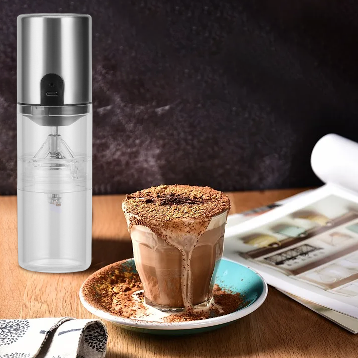 Ein elektrischer Kaffeemühlen-Prototyp neben einem Glas Kakao mit Kakaopulver bestäubt.
