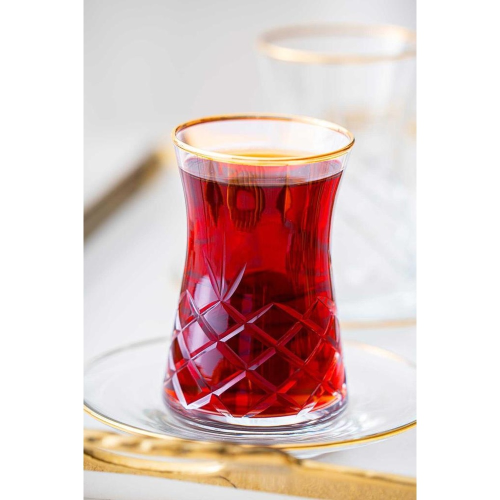 Altın kenarlı kırmızı çay bardağı fincan tabağında duruyor.