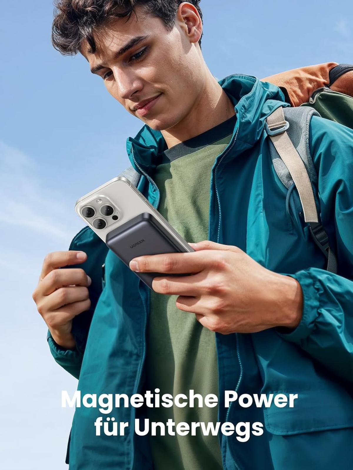 Uomo tiene uno smartphone con caricabatterie magnetico, cielo blu