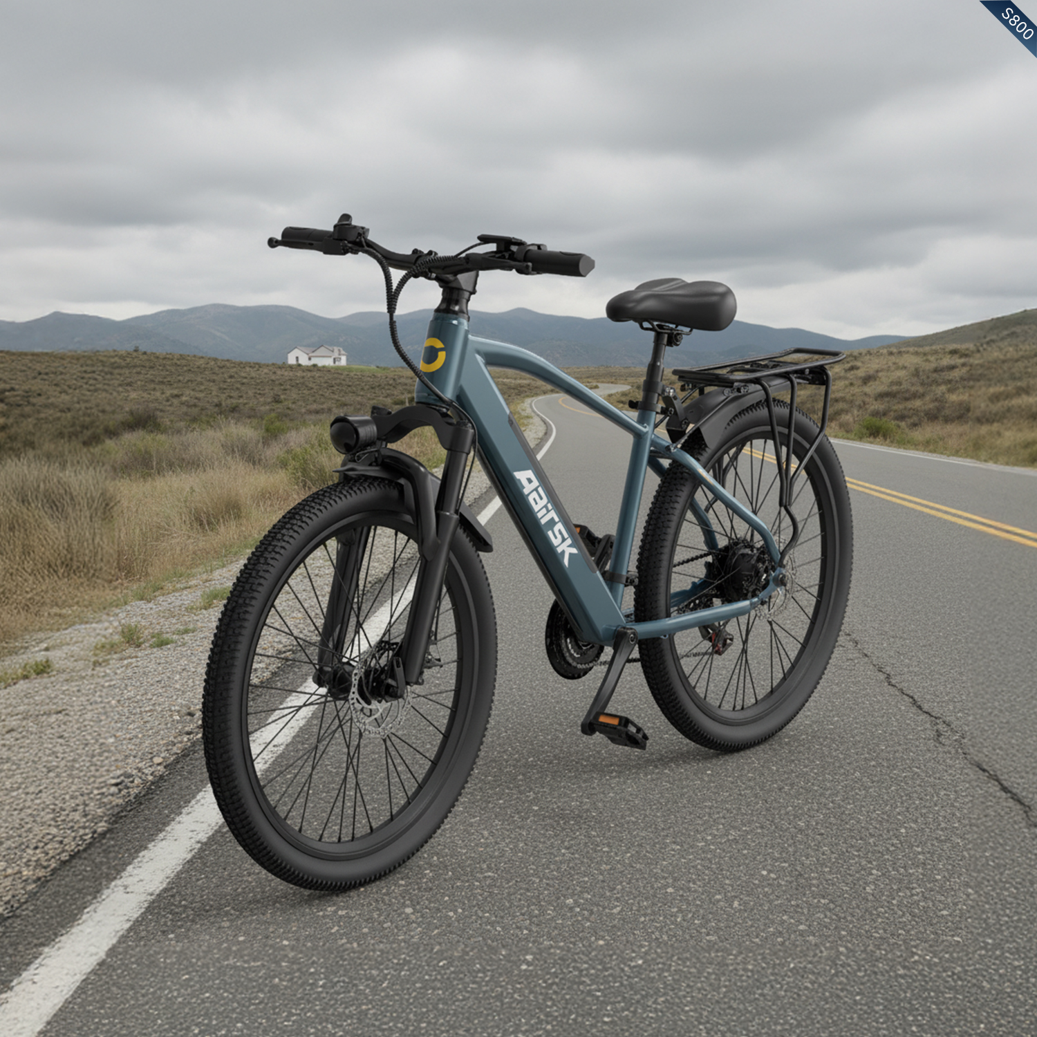 Una bicicletta elettrica blu si trova su una strada asfaltata con montagne sullo sfondo.