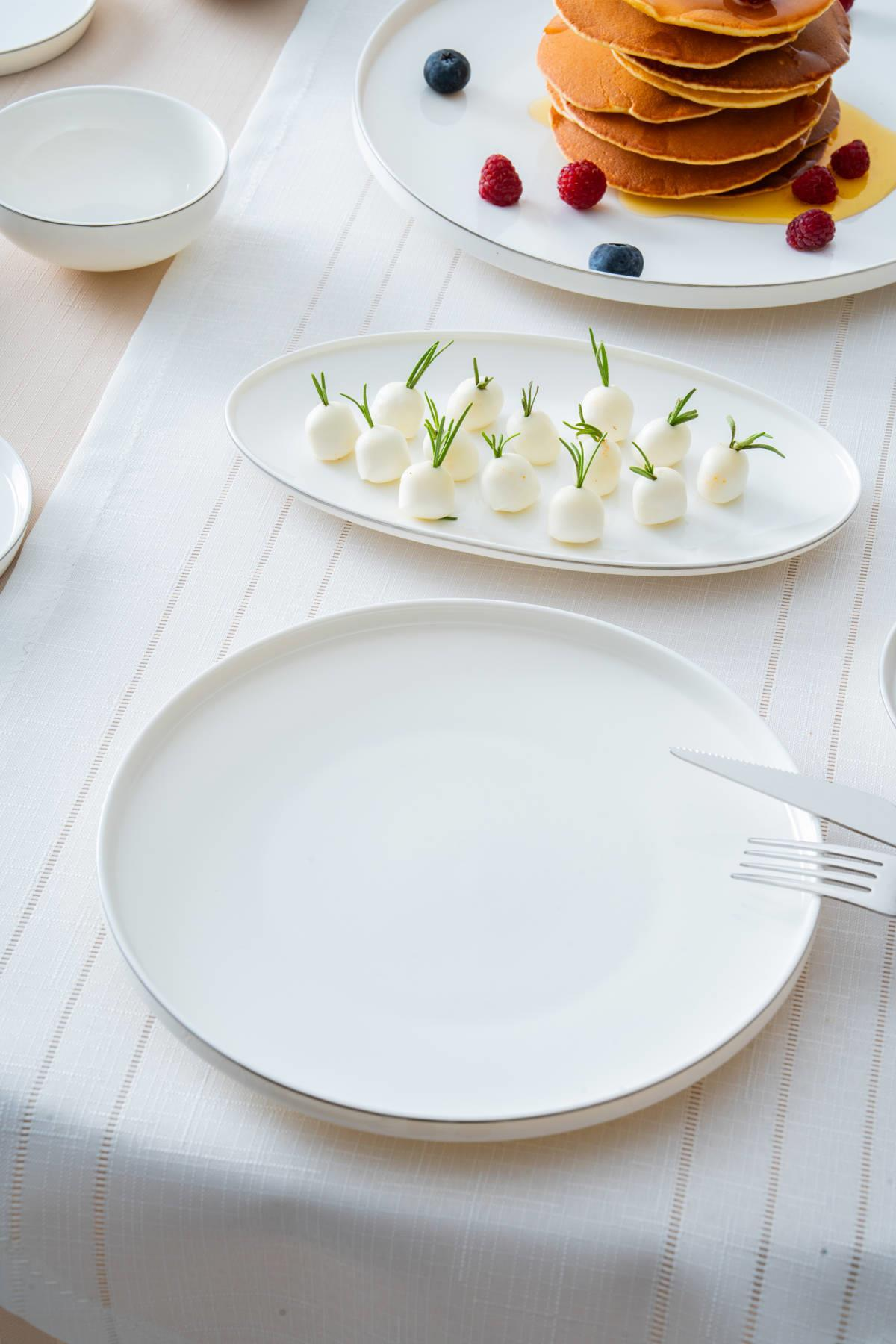 Rozemarinli peynir topları ve arkada pankeklerin yanında çatal bıçak takımı.