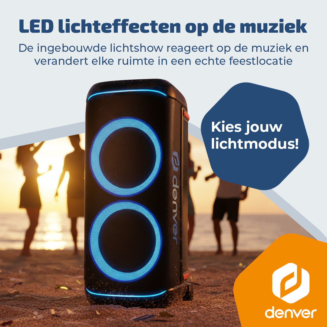 Een zwarte speaker met blauwe LED-ringen staat op het strand. Mensen dansen op de achtergrond.