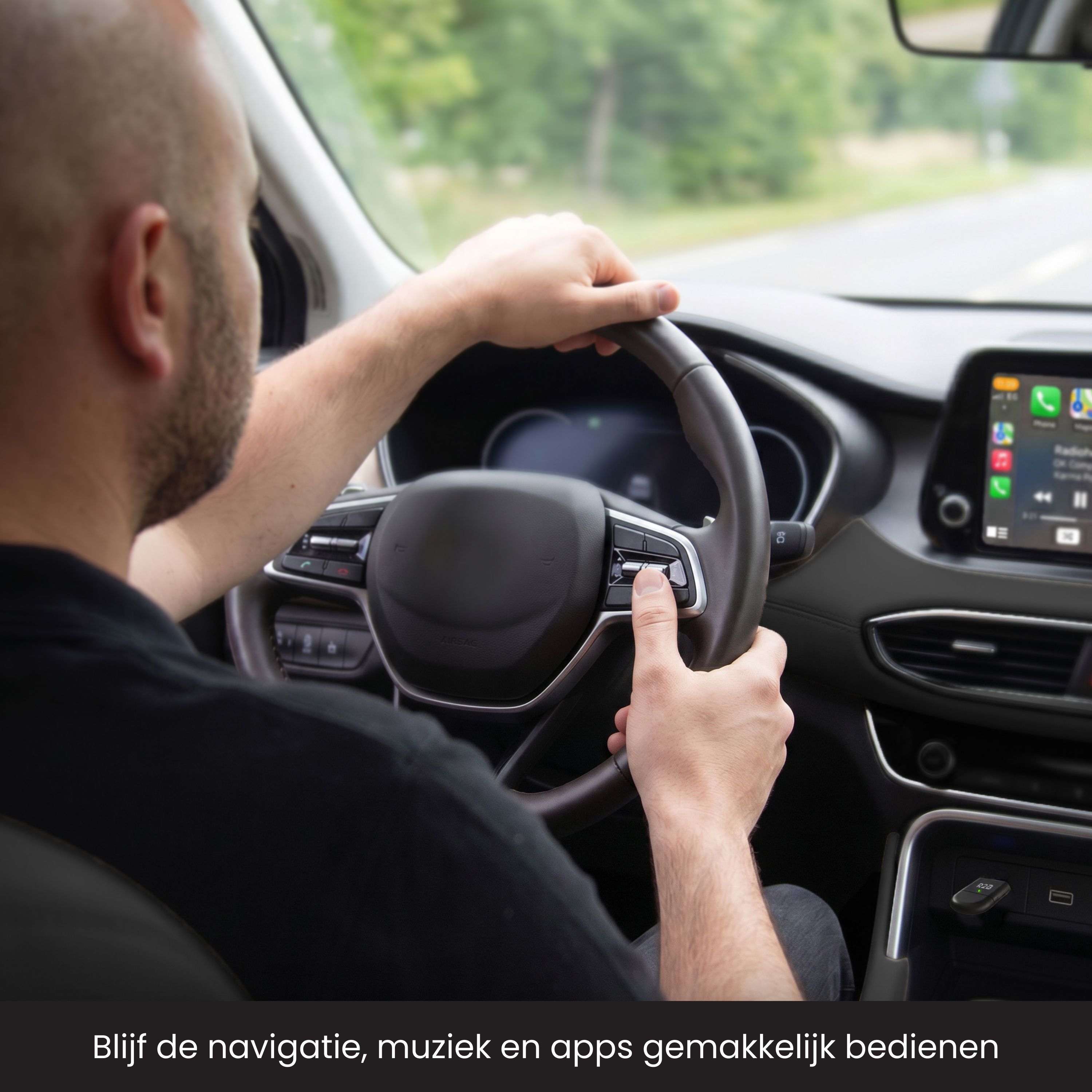 Man rijdt auto, bedient infotainment via stuurwielknoppen. Groene natuur buiten.