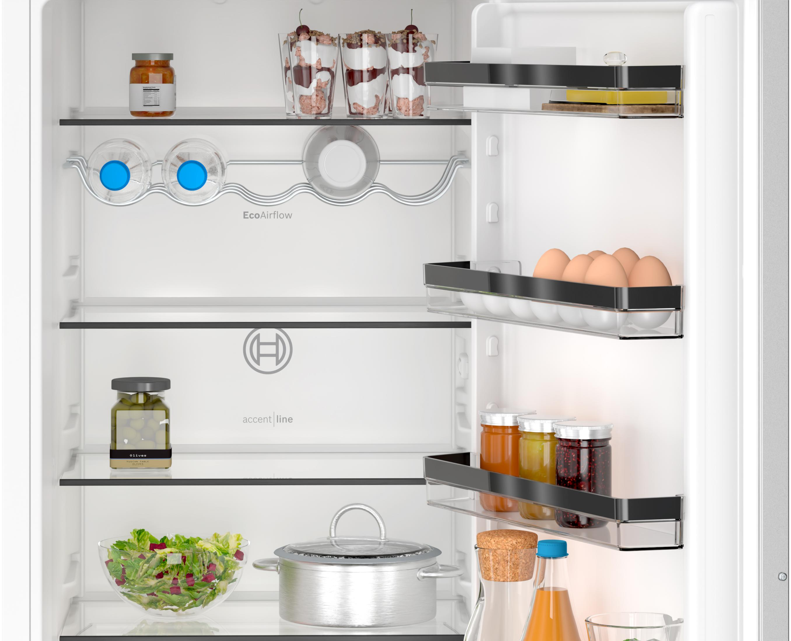 Refrigerador abierto con frascos, vasos, huevos, pepinillos y ensalada.