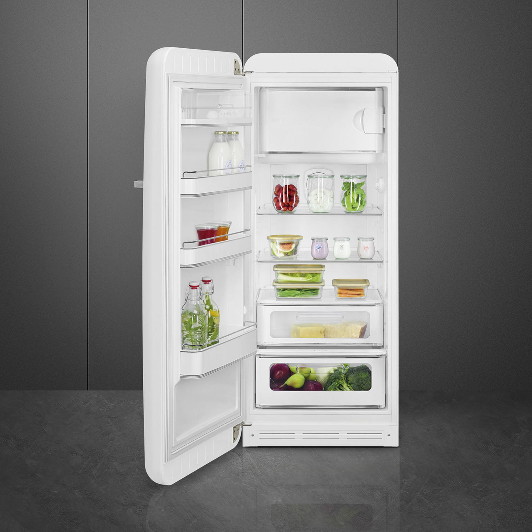 Un frigorifero bianco con la porta aperta, riempito con cibi come frutta, verdura e bottiglie.
