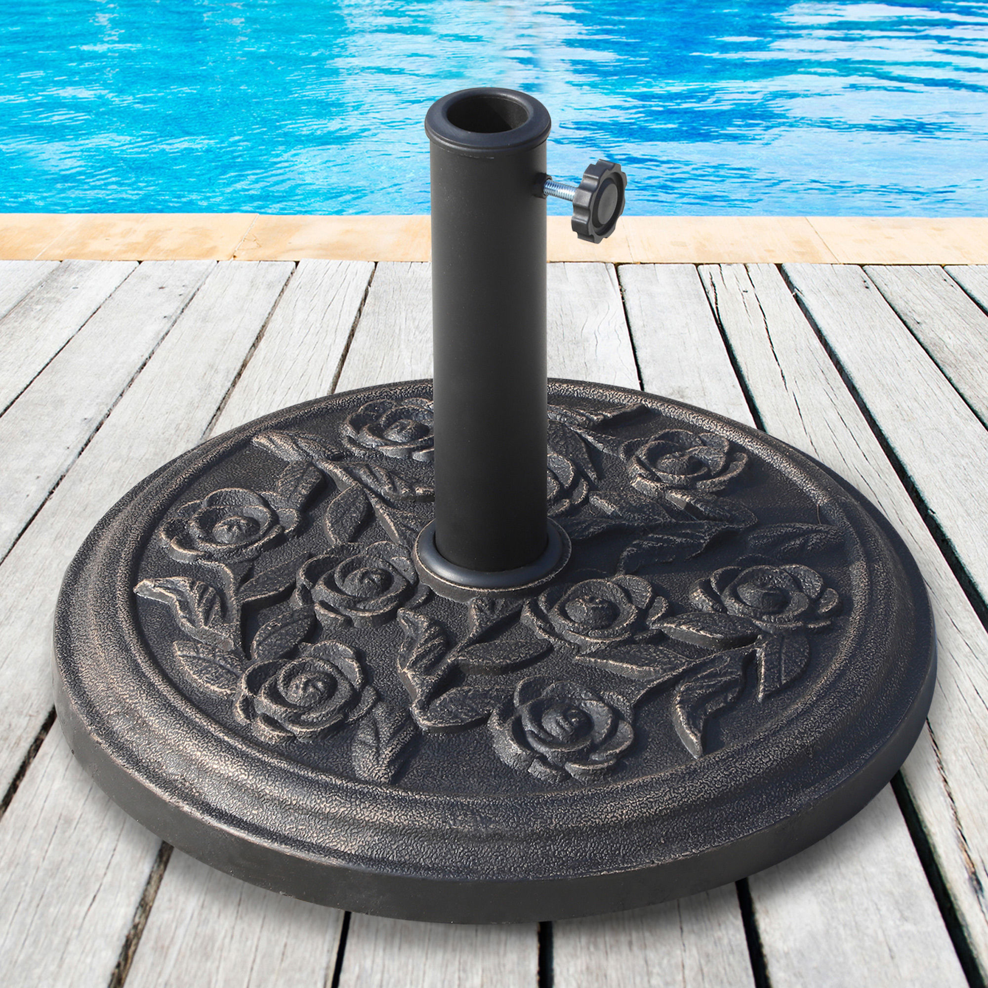Una pesada base de sombrilla con patrón de rosas sobre tablones de madera junto a una piscina.