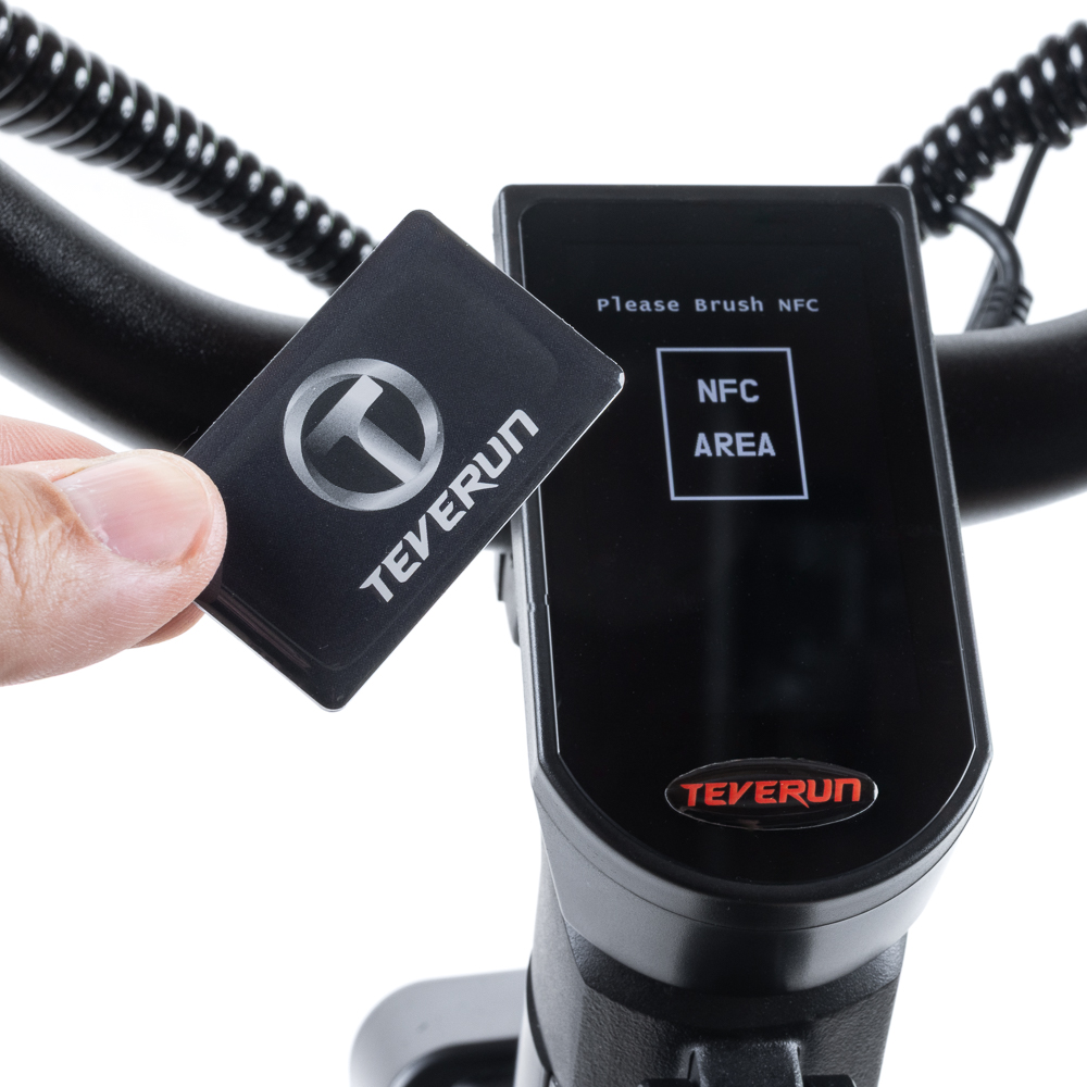 Main tenant une carte Teverun près de la zone NFC sur l'écran noir d'un scooter.