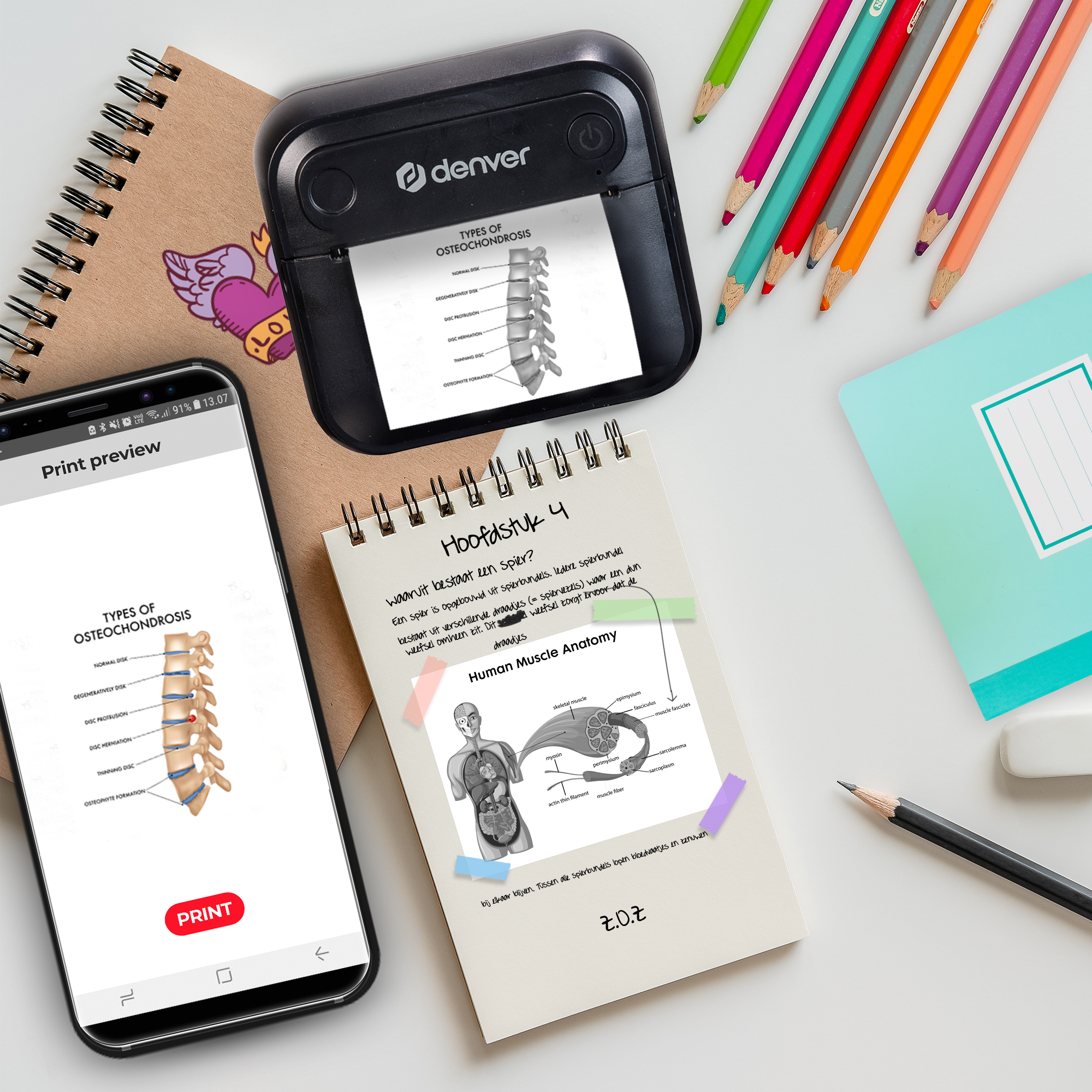 A phone shows a spine print, beside it a printer and colored pencils.
