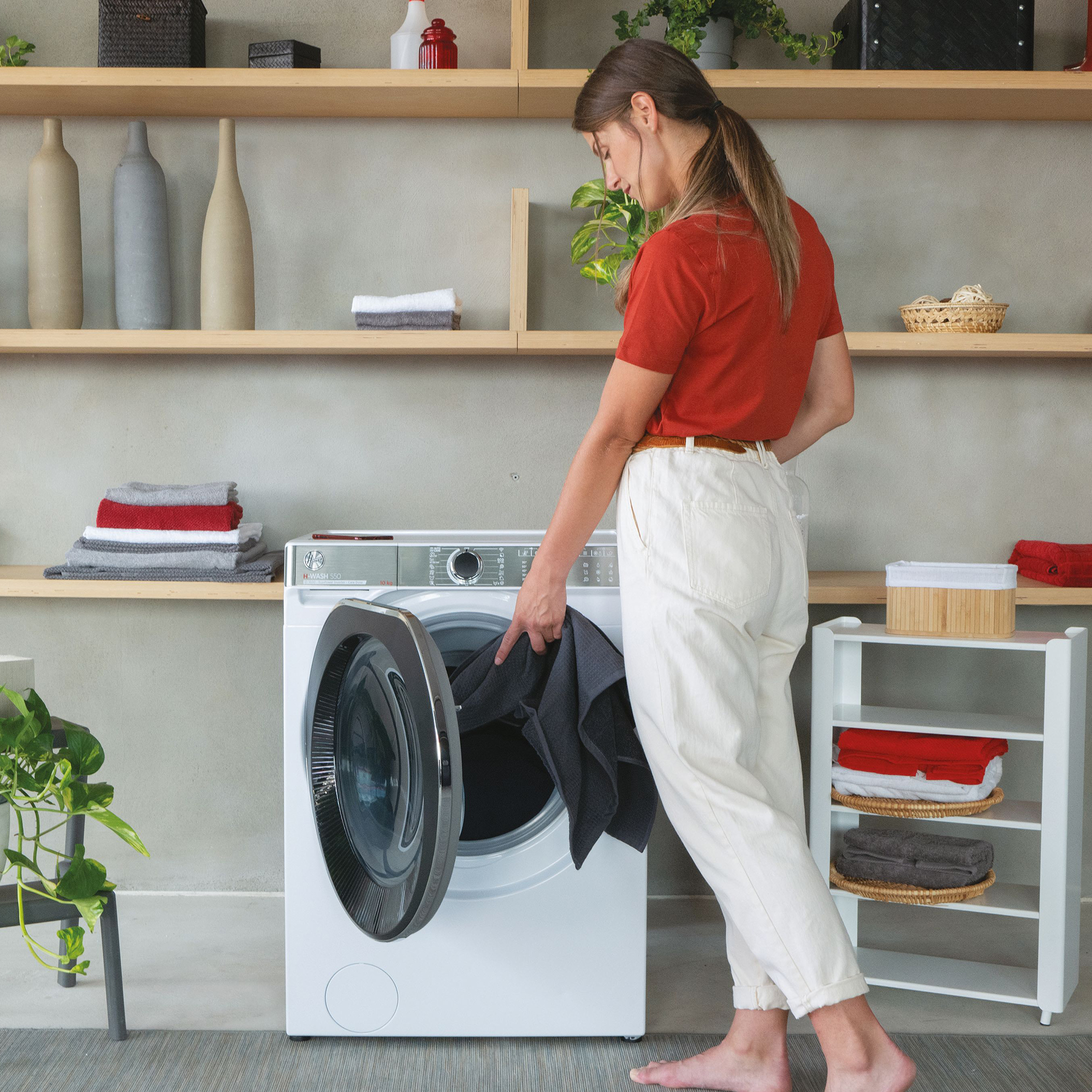 Eine Frau lädt dunkle Wäsche in eine weiße Waschmaschine.